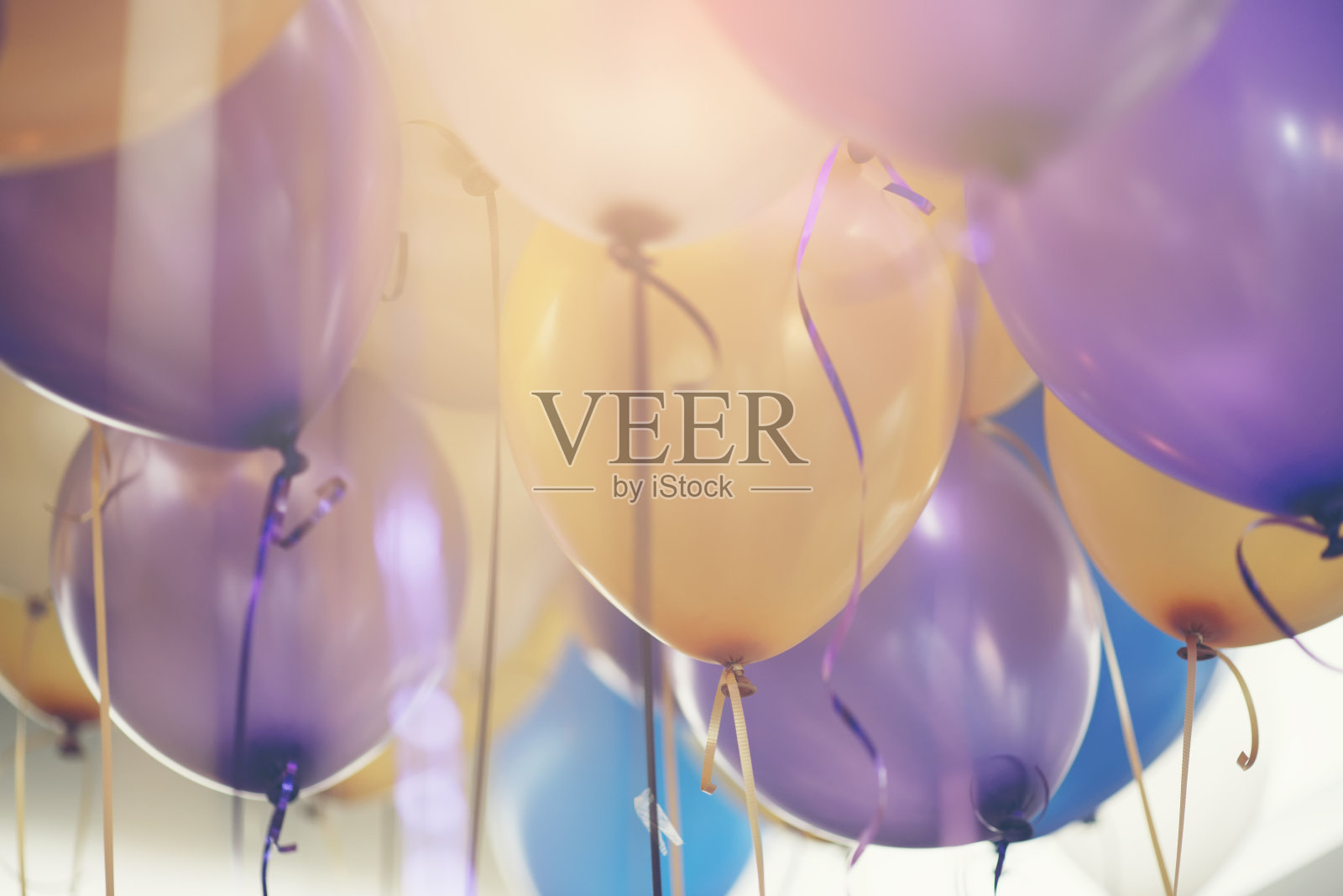 生日派对背景中的气球。多色(黄，蓝，紫，紫)氦气球与丝带庆祝婚礼的日子。婚礼和生日派对气球的概念。照片摄影图片