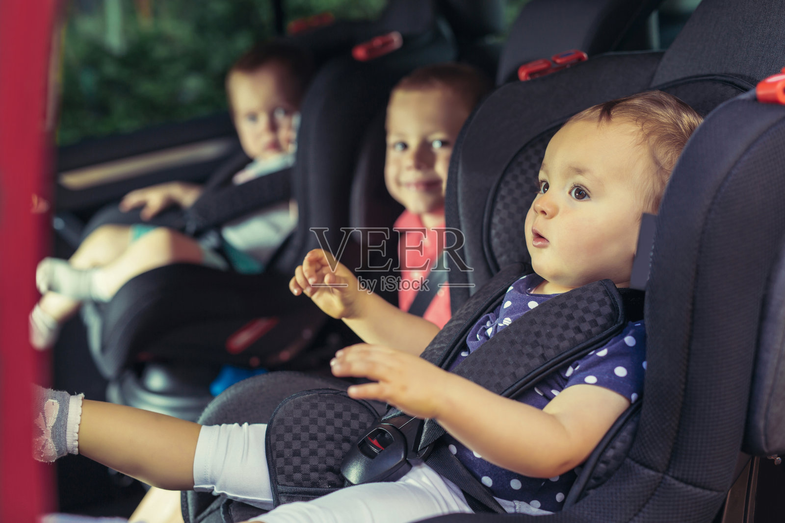 三个孩子坐在汽车安全座椅上照片摄影图片