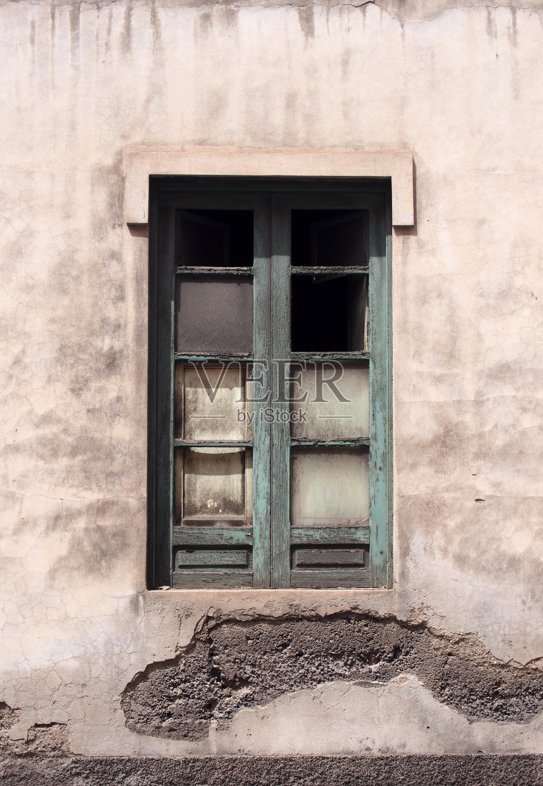 一间被遗弃的房子里，油漆成绿色的破窗，混凝土墙剥落，玻璃缺失照片摄影图片