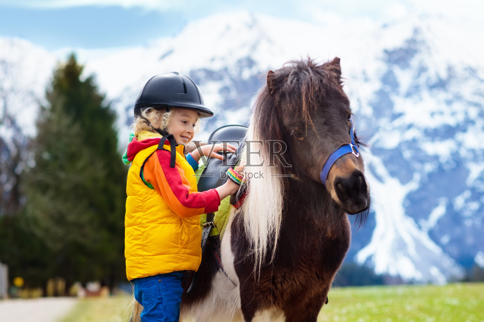 孩子们骑小马。阿尔卑斯山山上骑着马的孩子照片摄影图片