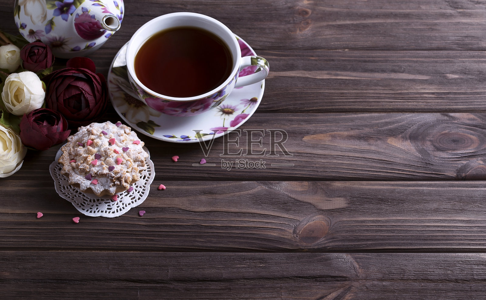 茶壶、茶杯和蛋糕放在棕色的木桌上。照片摄影图片