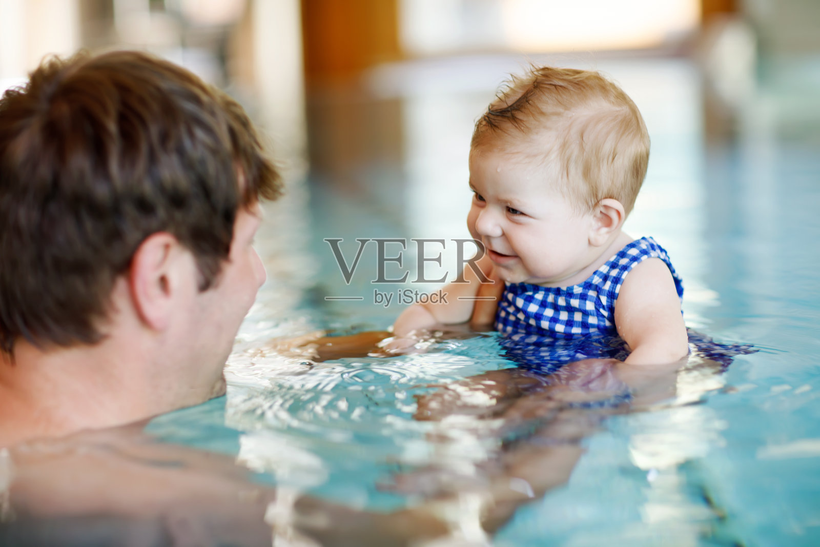 快乐的中年父亲和可爱的小女孩在游泳池游泳。照片摄影图片