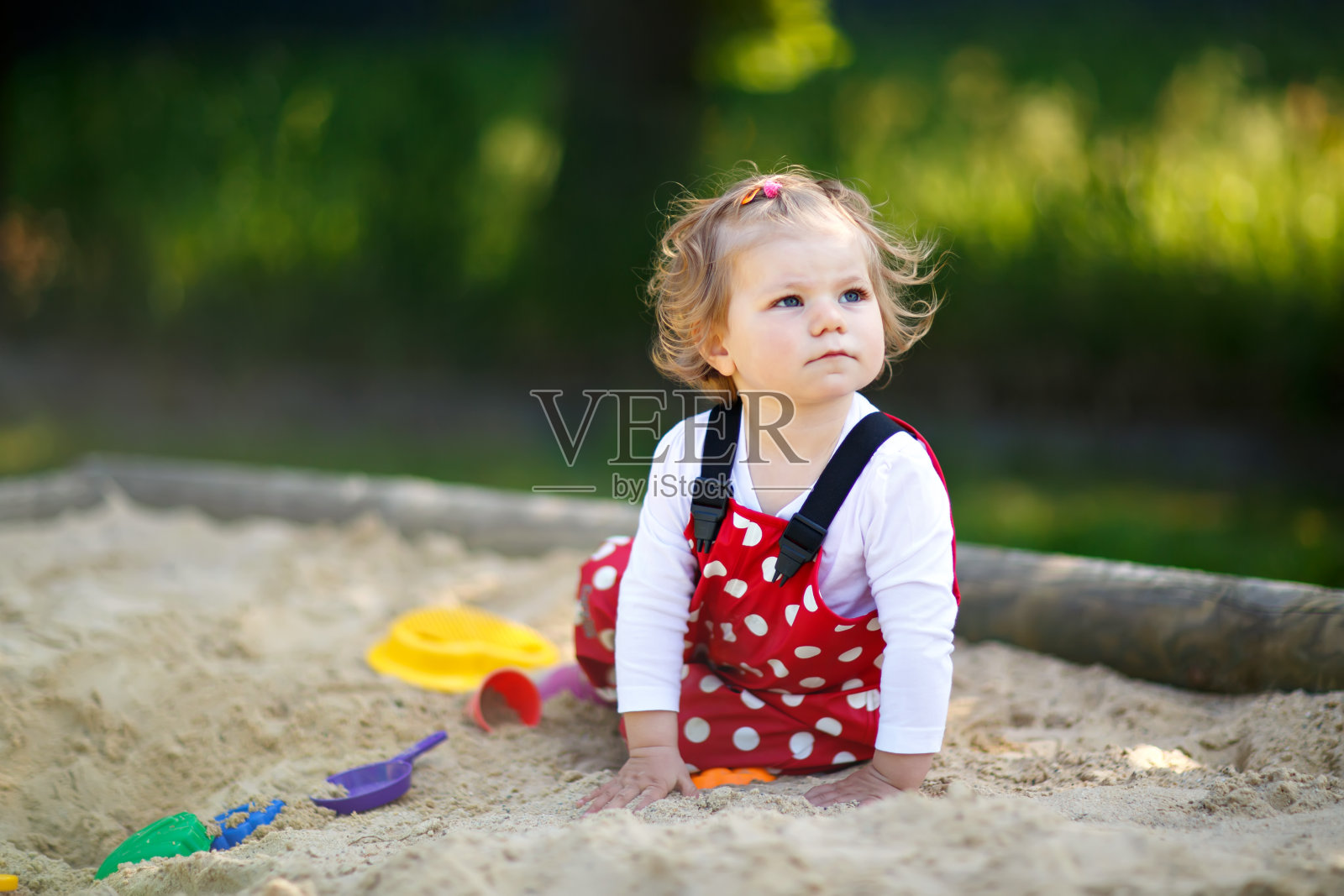 可爱的蹒跚学步的小女孩在户外操场上玩沙子。美丽的婴儿在红色的口香糖裤子有乐趣在阳光明媚温暖的夏天。照片摄影图片