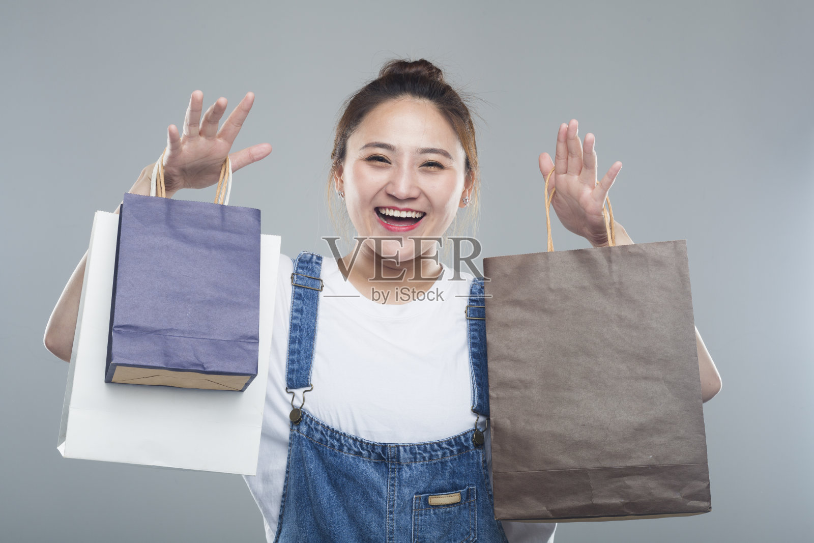 在灰色的背景下，兴高采烈的女人拿着购物袋照片摄影图片