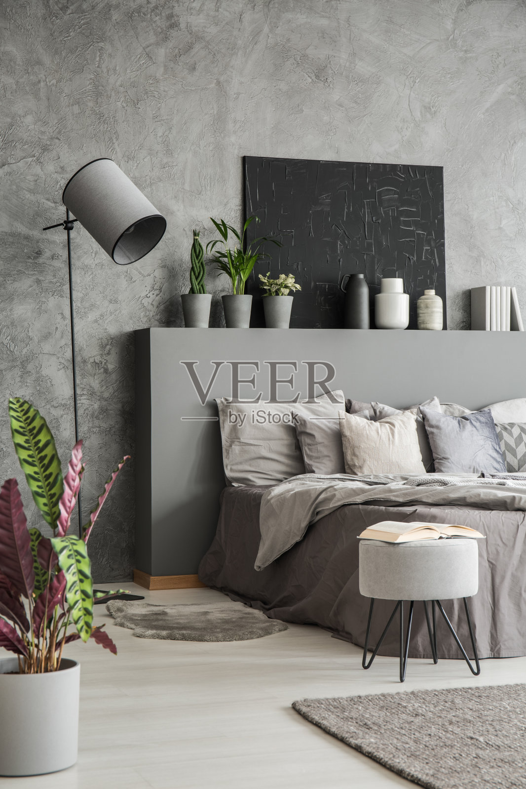 植物，凳子和灯在现代灰色的卧室内部与海报在床上。真实的照片照片摄影图片