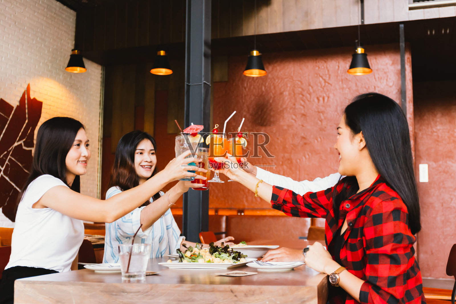 一群亚洲快乐和微笑的年轻男子和妇女拿着酒精鸡尾酒祝酒和庆祝在社交聚会在餐厅ใ照片摄影图片