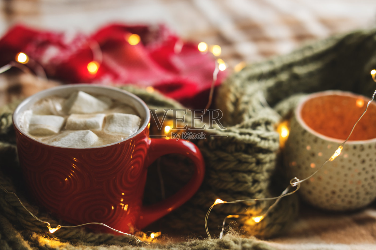 秋天的静物南瓜，树叶，松果，蜡烛，围巾，红色的可可杯，咖啡或热巧克力与棉花糖在温暖的格子花环。舒适的冬季家居环境概念。照片摄影图片