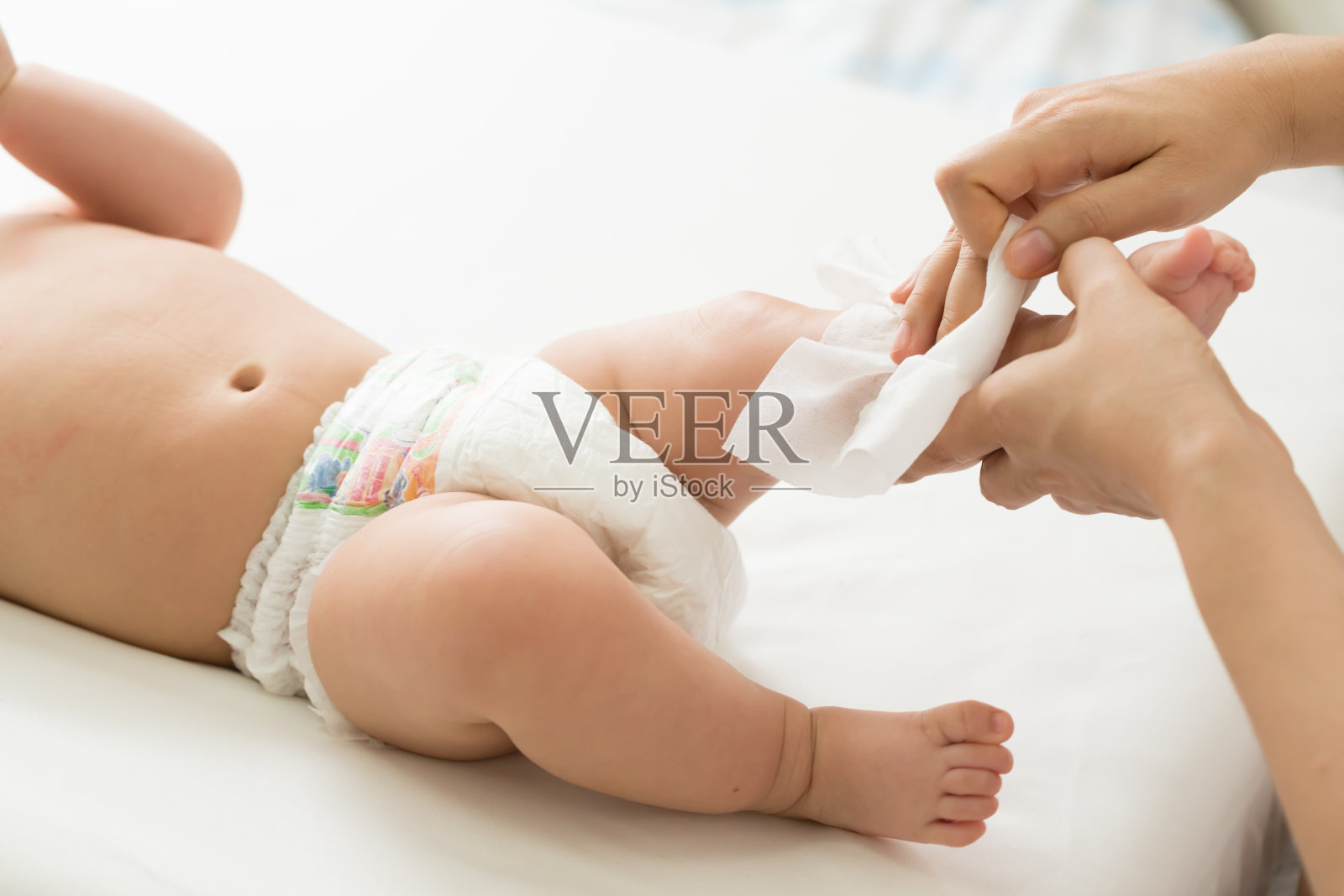 妈妈一边打扫，一边用湿纸巾擦拭宝宝的身体和腿照片摄影图片