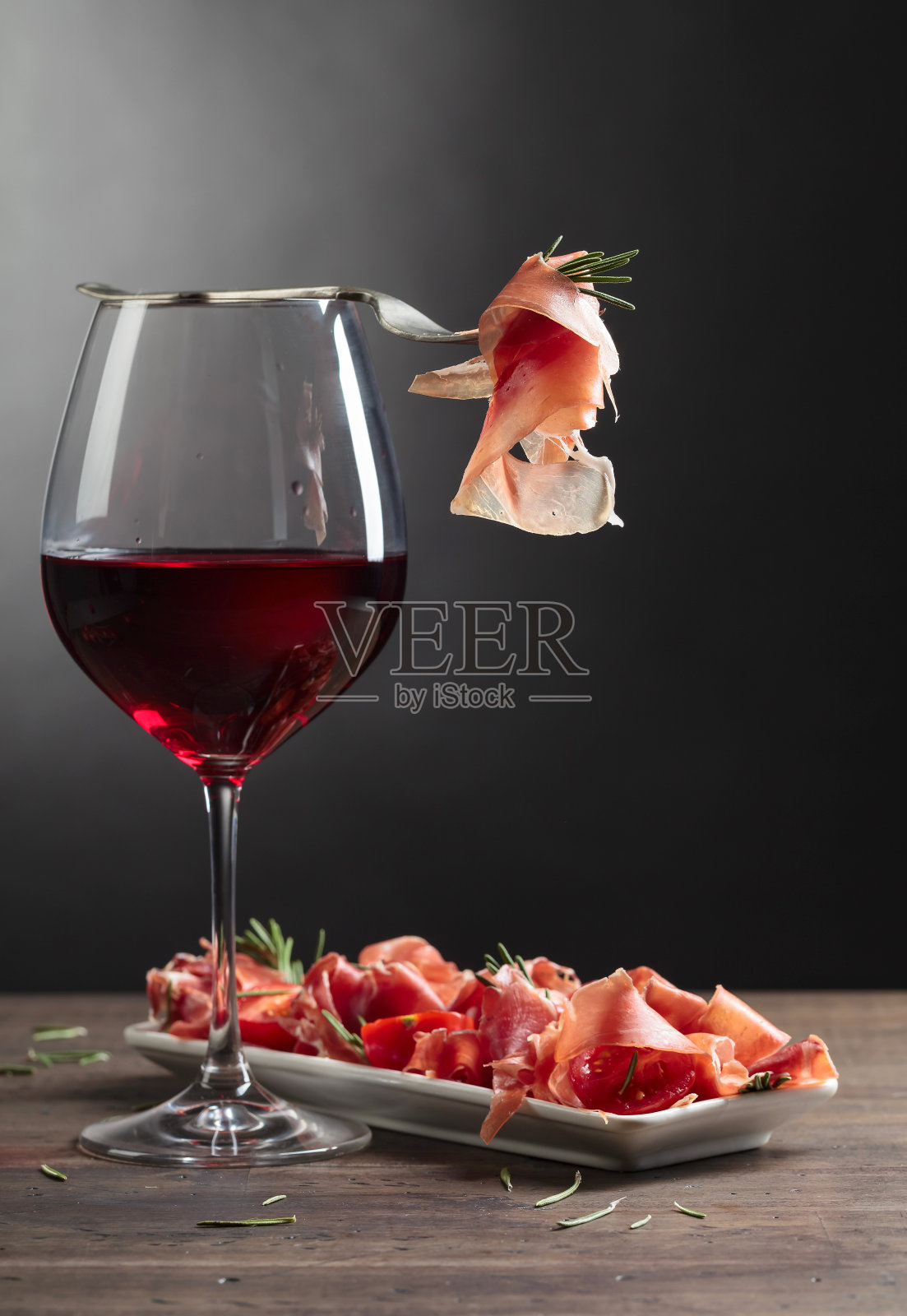 熏火腿配红酒，迷迭香和番茄樱桃放在旧木桌上。照片摄影图片