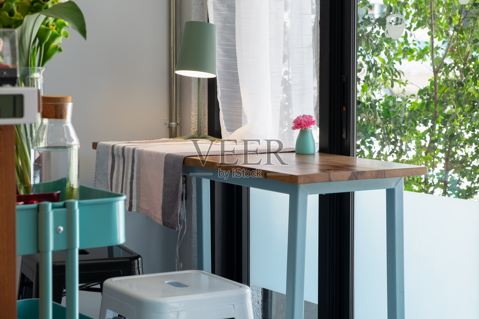 绿色的灯和盆栽植物放在木制桌椅上，白色的小空间靠近窗户和外面的花园。客厅，家庭桌子和最小面积的概念。照片摄影图片