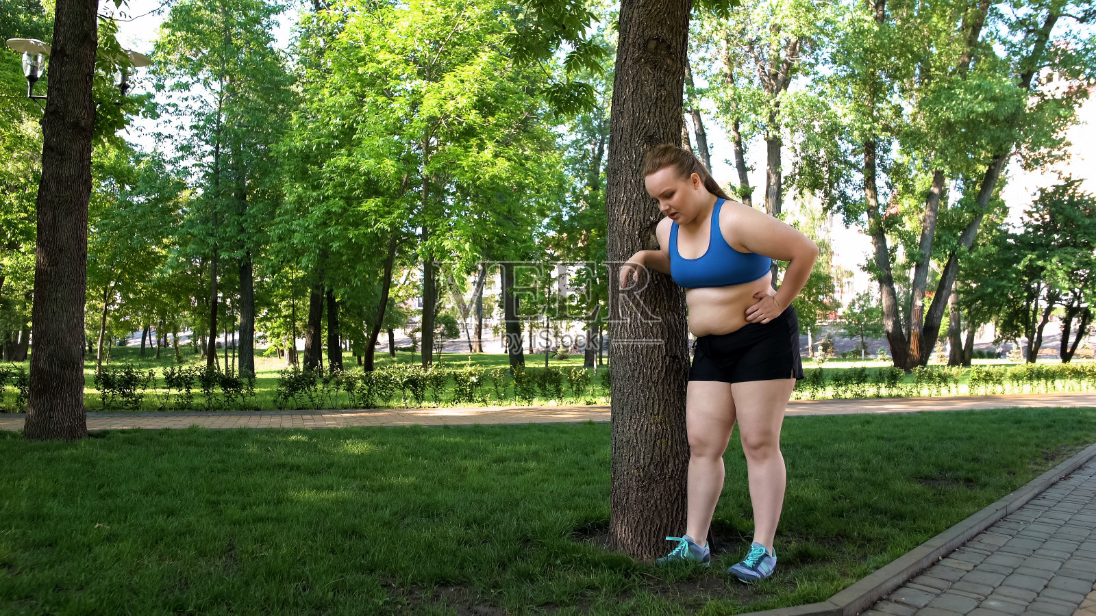 胖女孩在慢跑、靠在树上、户外无聊的锻炼后疲惫不堪照片摄影图片