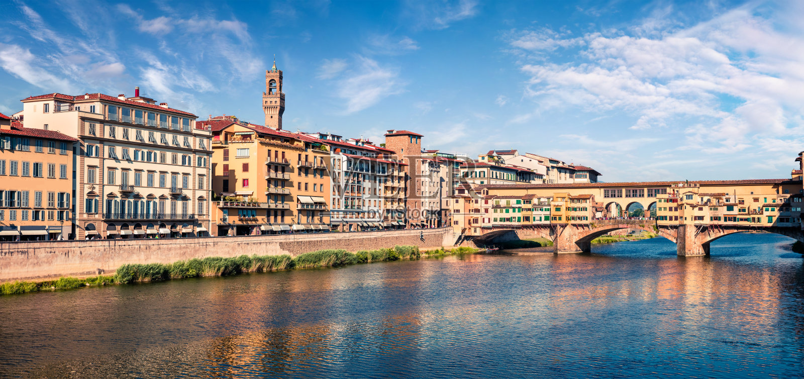 阳光明媚的春天佛罗伦萨与老宫殿(Palazzo Vecchio或Palazzo della Signoria)的背景和阿尔诺河上的韦基奥桥。色彩缤纷的早晨，在意大利，欧洲。照片摄影图片