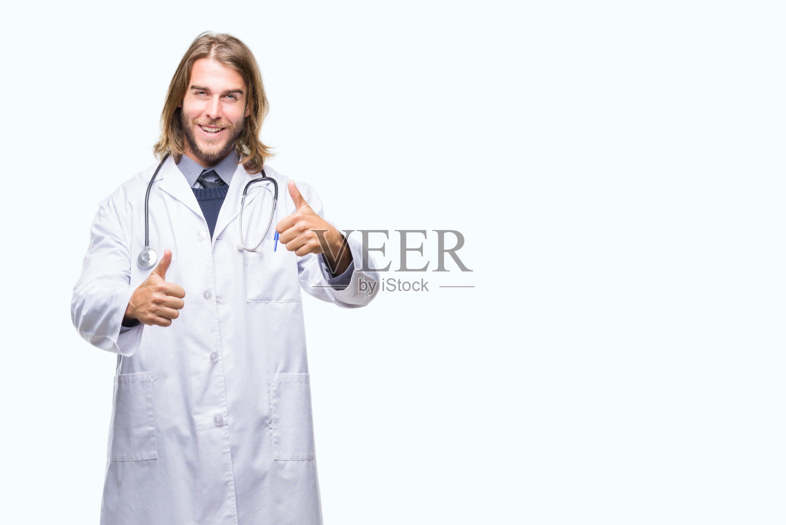 年轻英俊的医生男人长头发在孤立的背景赞成做积极的手势与手，大拇指向上微笑和为成功而高兴。看着镜头，胜利者的手势。照片摄影图片