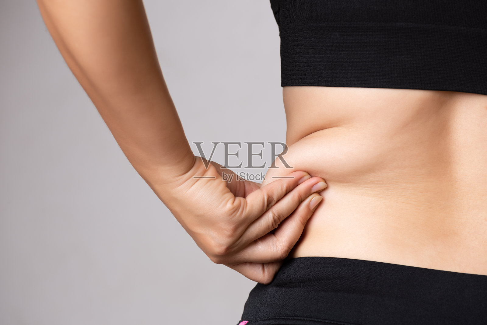 胖女人手牵着肚子上过多的脂肪。保健和女性饮食生活理念，以减少腹部和塑造健康的腹部肌肉。照片摄影图片