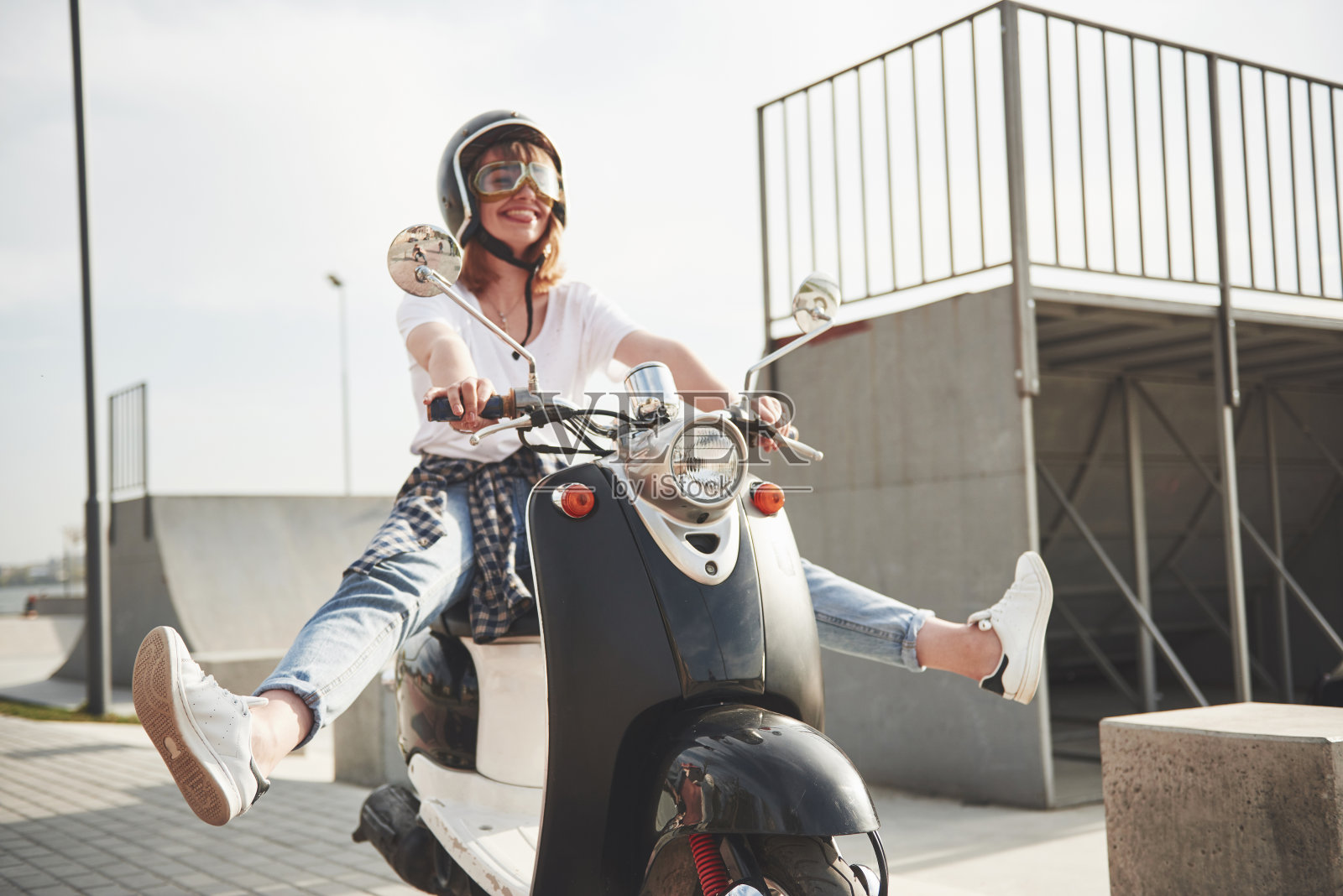 一个漂亮的女孩嬉皮士的肖像坐在一个黑色复古摩托车，微笑摆姿势，享受温暖的春天的阳光。照片摄影图片
