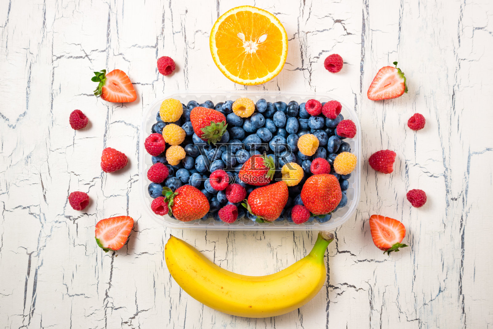 浆果和水果背景。新鲜蓝莓，草莓，覆盆子，香蕉和橙子放在白色的桌上。夏日浆果。健康食品、饮食观念。俯视图照片摄影图片