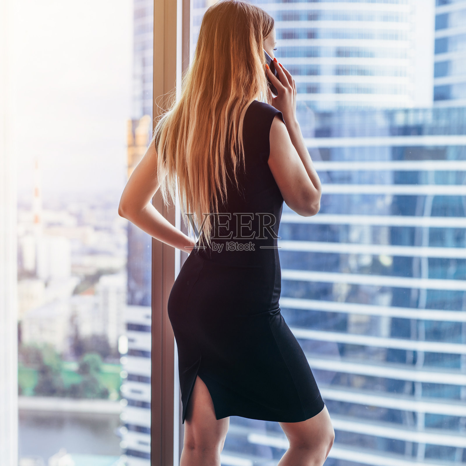 后视图的成功女商人有电话交谈看窗外与城市景观照片摄影图片