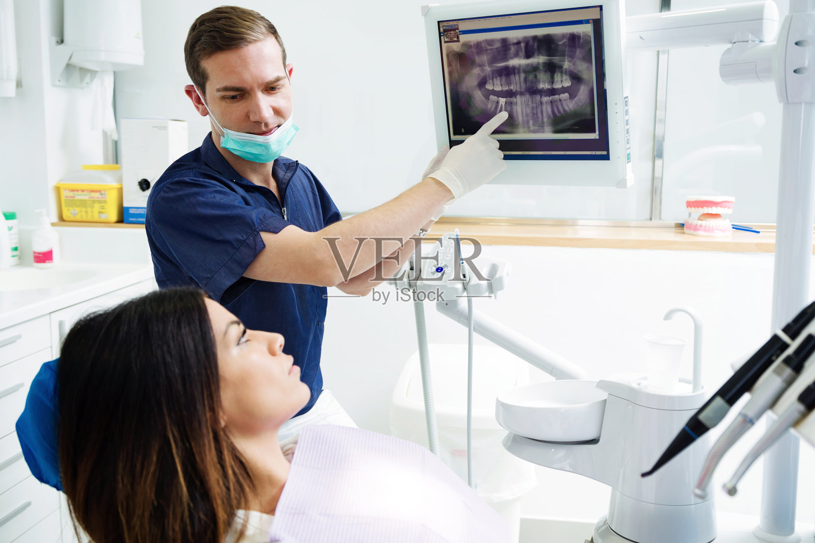 迷人的年轻牙医在牙科诊所向他的病人展示她的口腔x光片。照片摄影图片