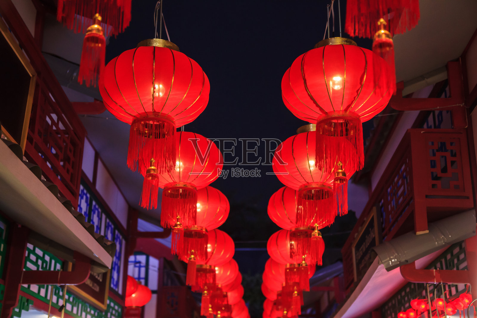 传统的中国红夜户外古董吊挂灯，用金色流苏装饰街道灯，建筑和商店庆祝春节照片摄影图片