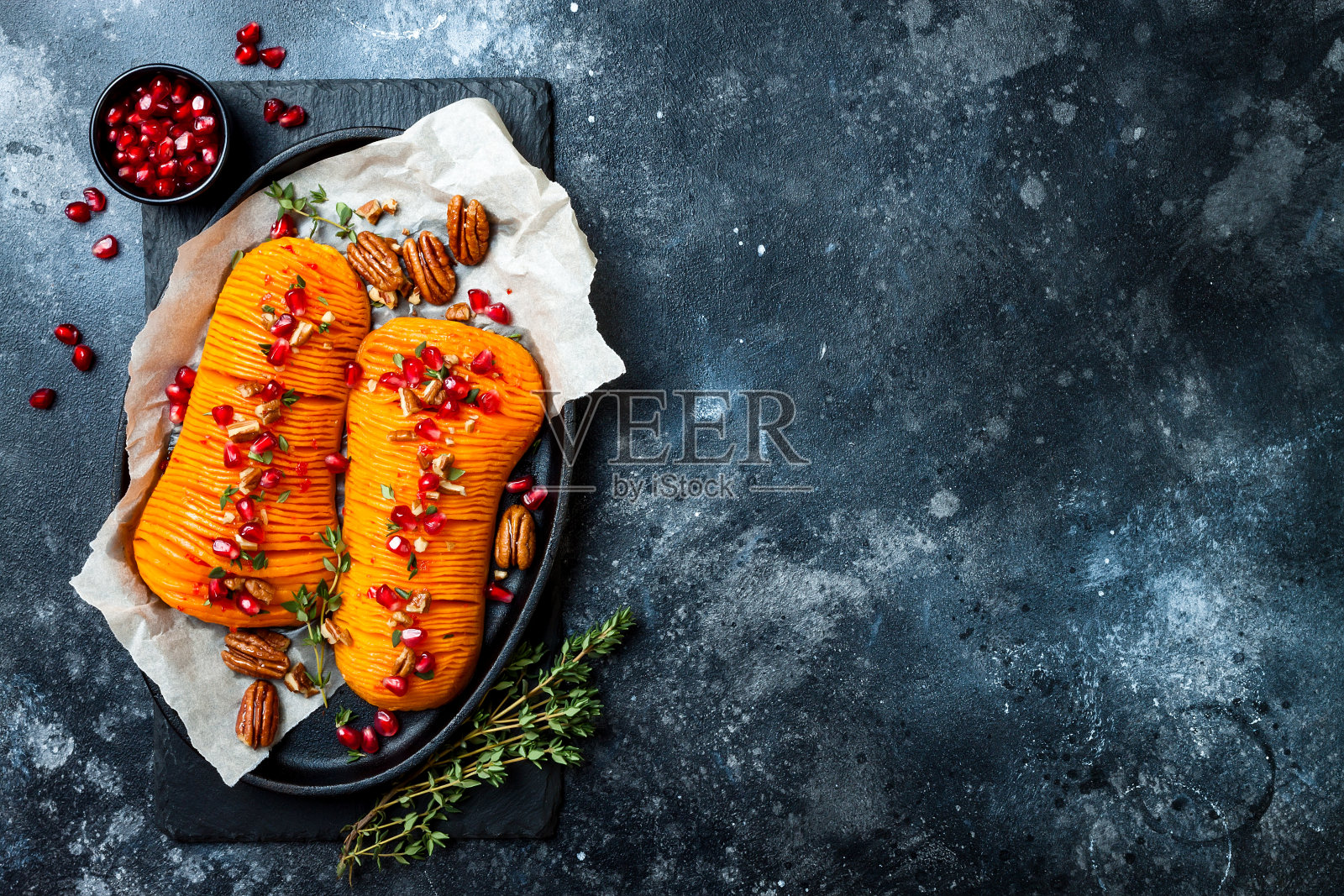 烤马背冬南瓜南瓜配百里香，山核桃和石榴。感恩节晚餐食谱。素食是健康的秋季或秋季食品照片摄影图片