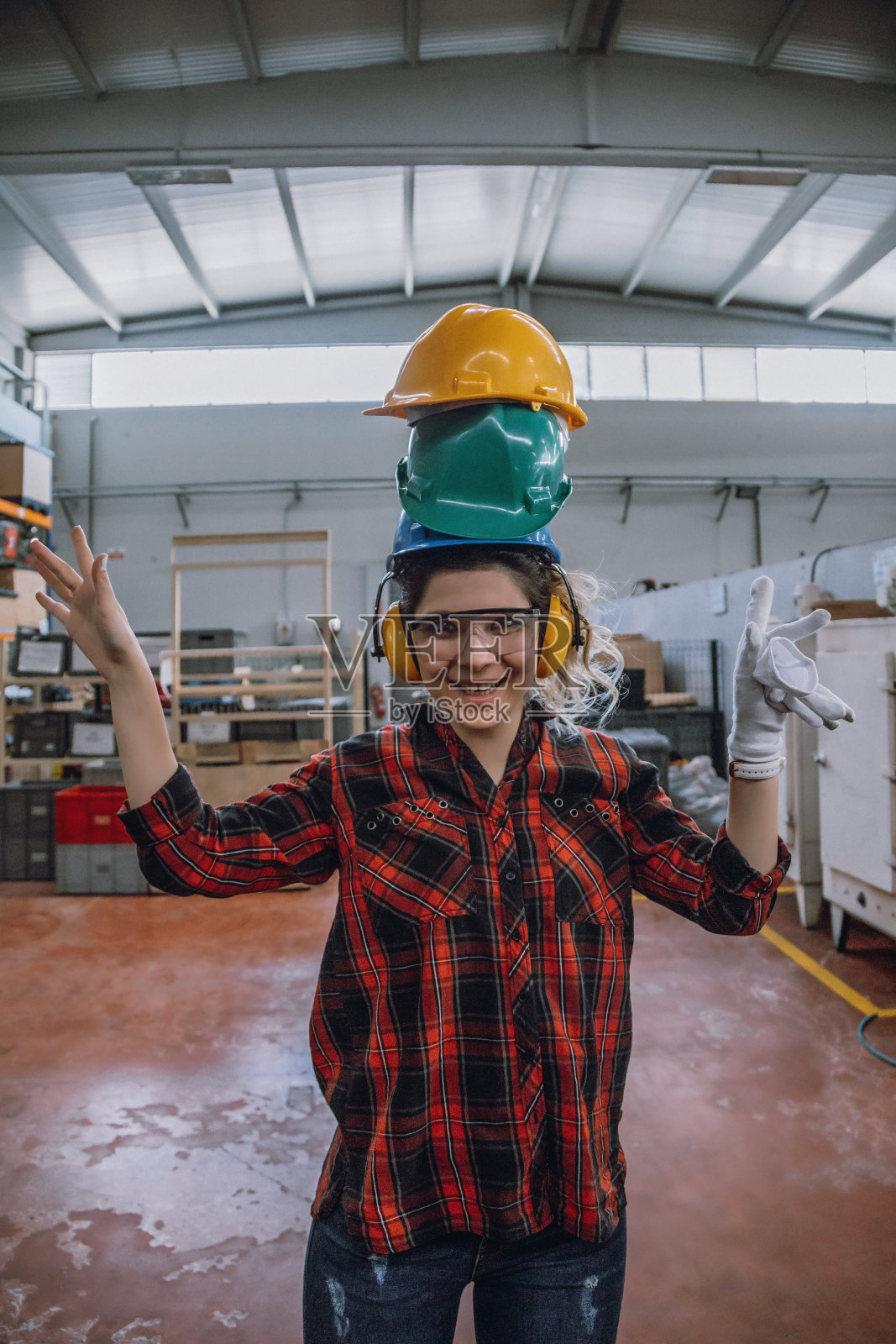 年轻女工业工人的肖像与工作头盔在工厂的乐趣照片摄影图片