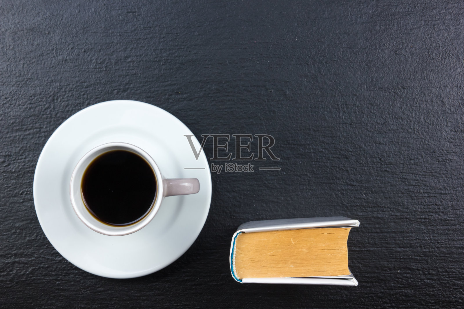一杯咖啡和一本书在黑色的木头背景。前视图。照片摄影图片
