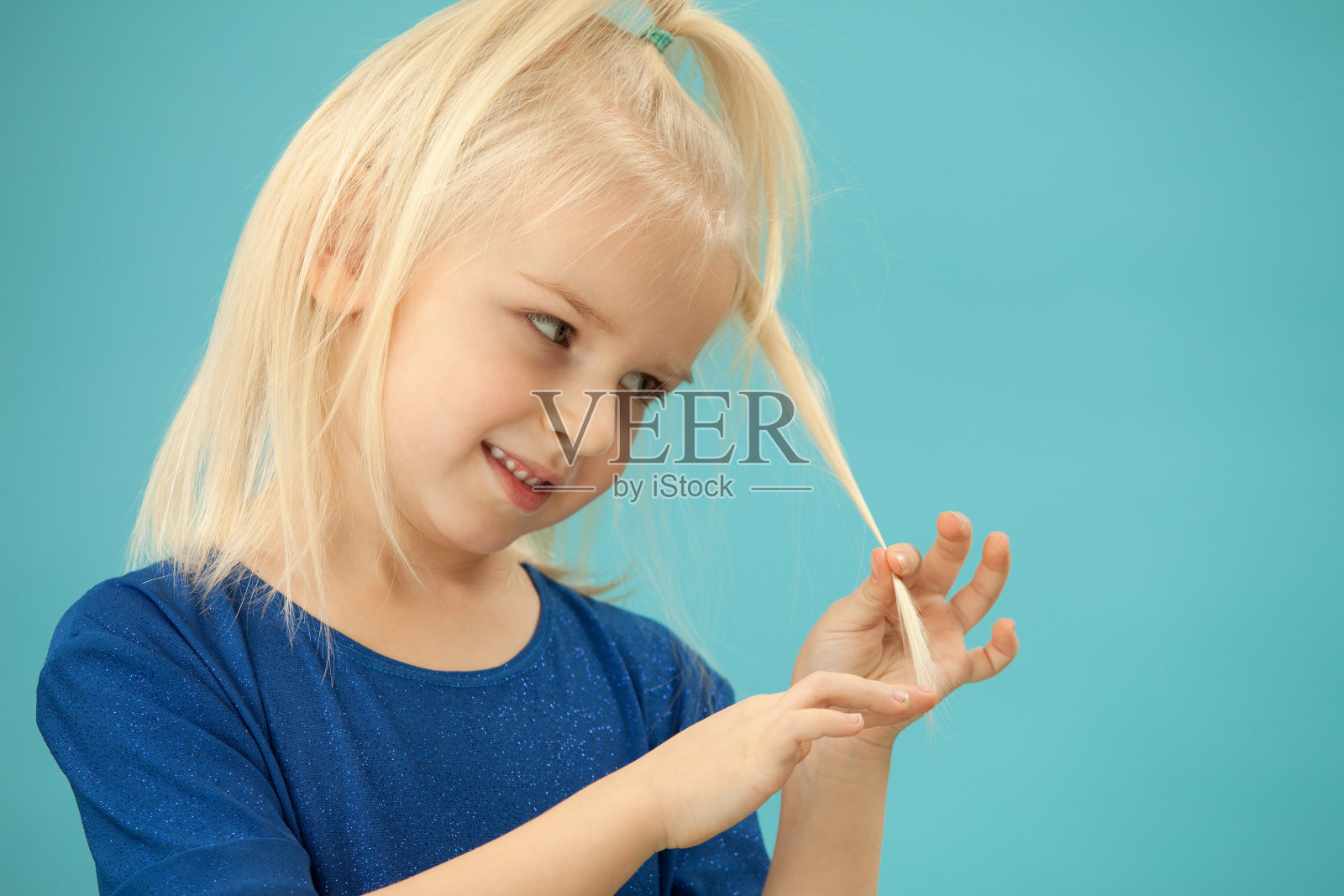 一个在蓝色背景上的4岁金发小女孩的工作室肖像照片摄影图片
