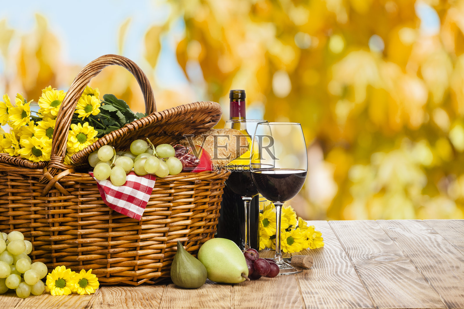 木桌子上的野餐篮子，映衬着稀疏的葱郁树叶照片摄影图片