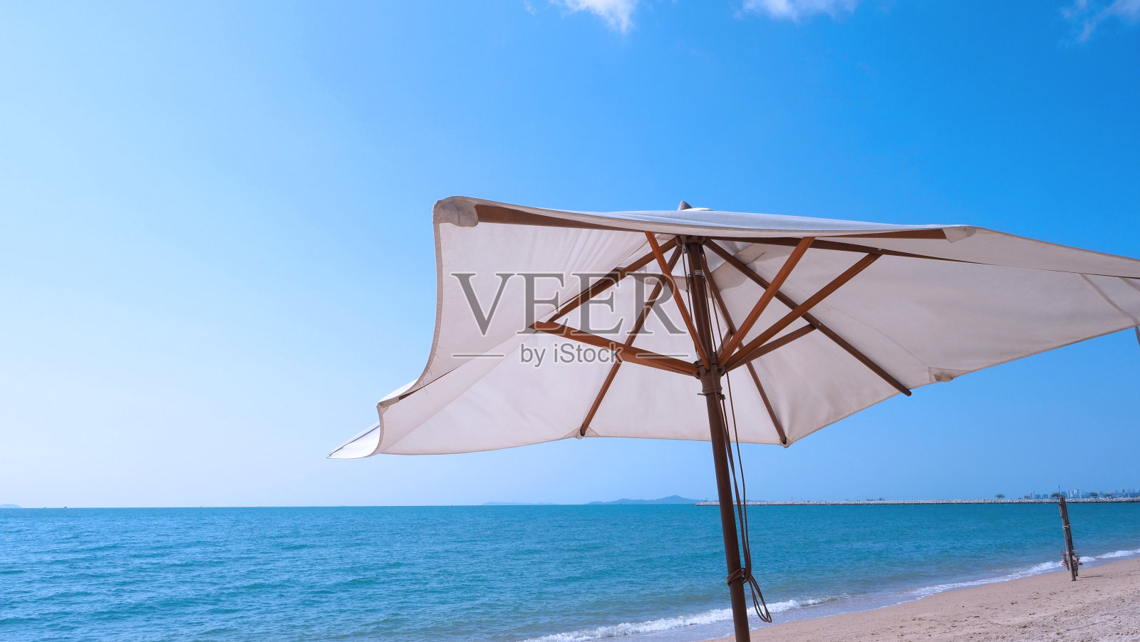 白色的织物颜色纹理沙滩伞和棕色的木三脚架与白云和晴朗的蓝天夏日阳光日低角度视角相机亚洲旅游泰国芭堤雅。照片摄影图片