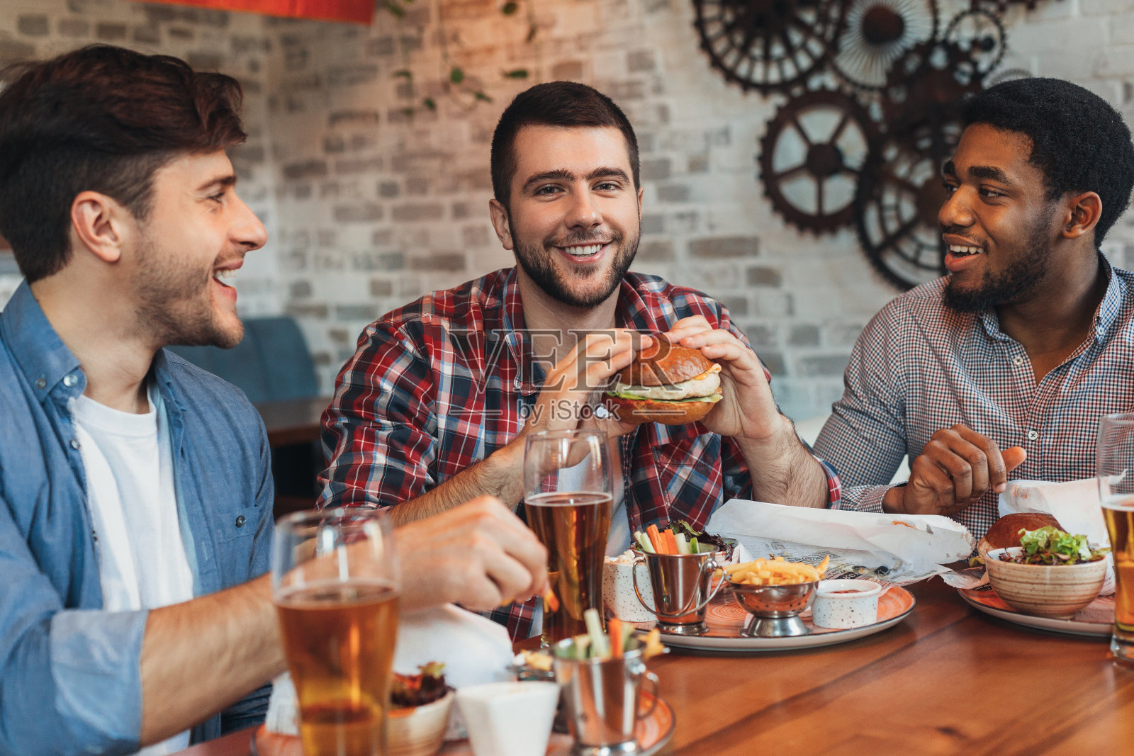 形形色色的朋友在酒吧里吃汉堡喝啤酒照片摄影图片