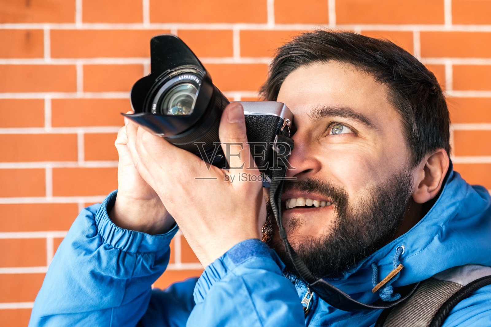 快乐年轻人的肖像。游客带着相机在城市里。砖墙的背景照片摄影图片