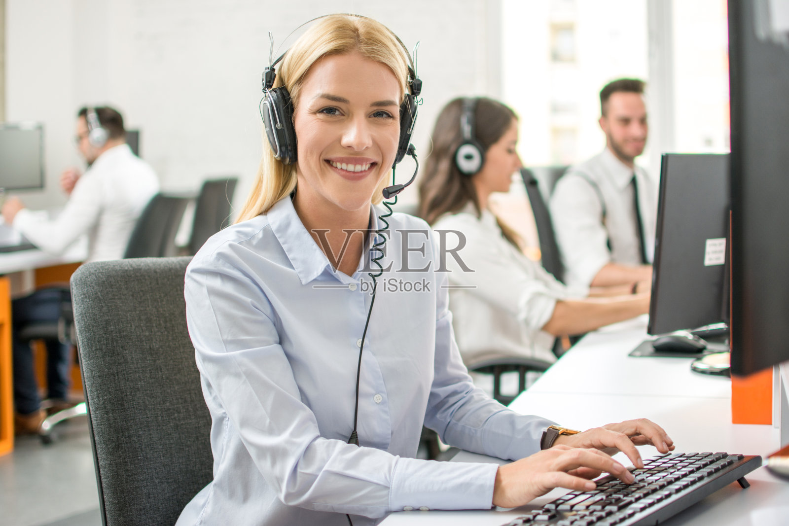 微笑的客户支持工作人员与耳机工作在呼叫中心的电脑照片摄影图片