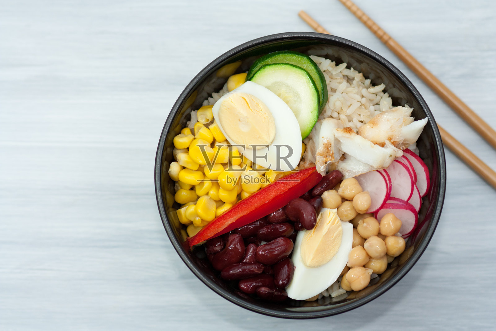 碗里有蔬菜、米饭和鱼。照片摄影图片