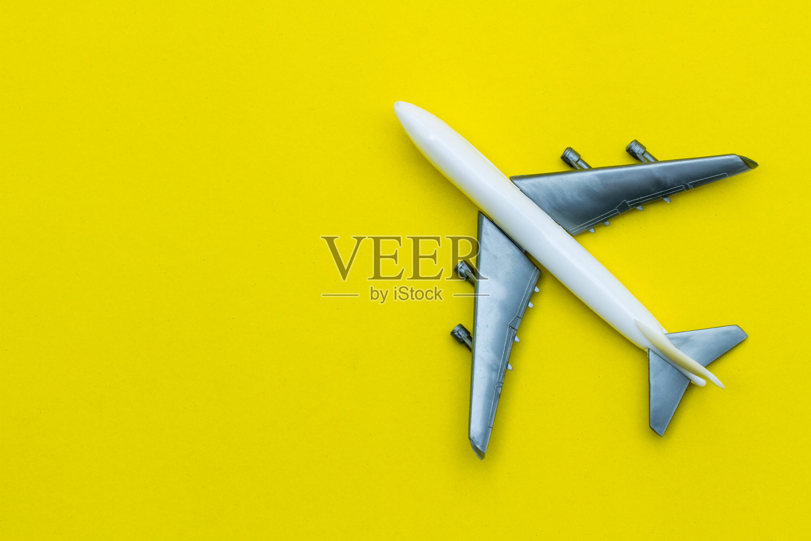 黄色背景上的微型玩具飞机。乘飞机旅行。照片摄影图片