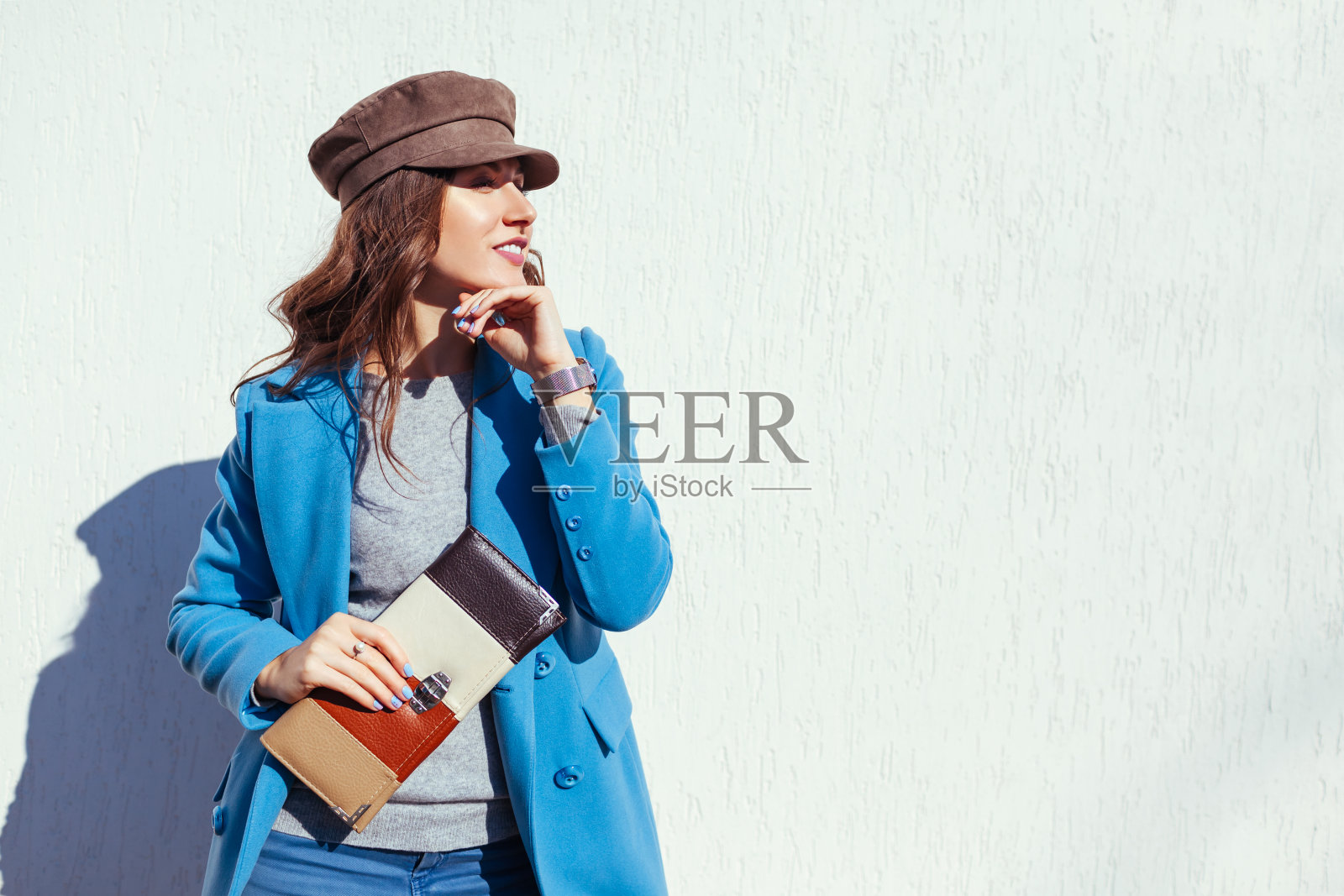 年轻女子拿着时髦的手提包，穿着时髦的蓝色外套。春季女性服饰配饰。时尚照片摄影图片