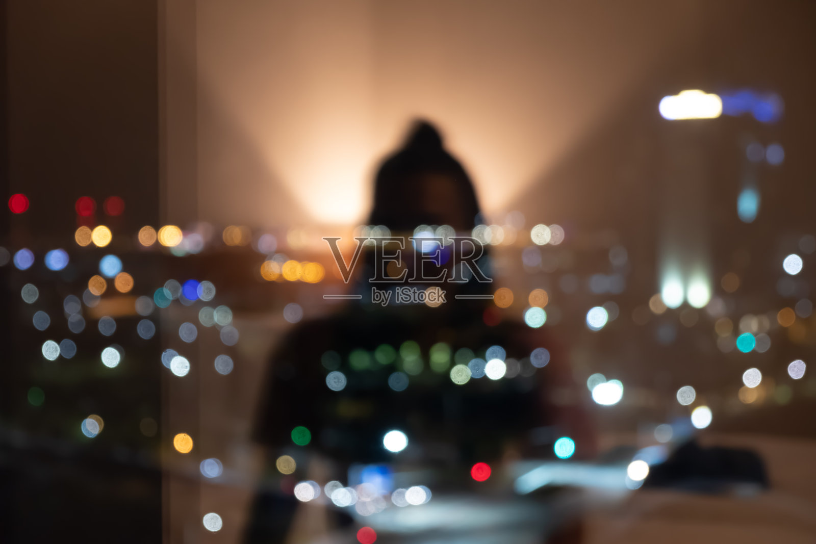 在城市灯光的映衬下，一个女孩从窗户里的倒影照片摄影图片