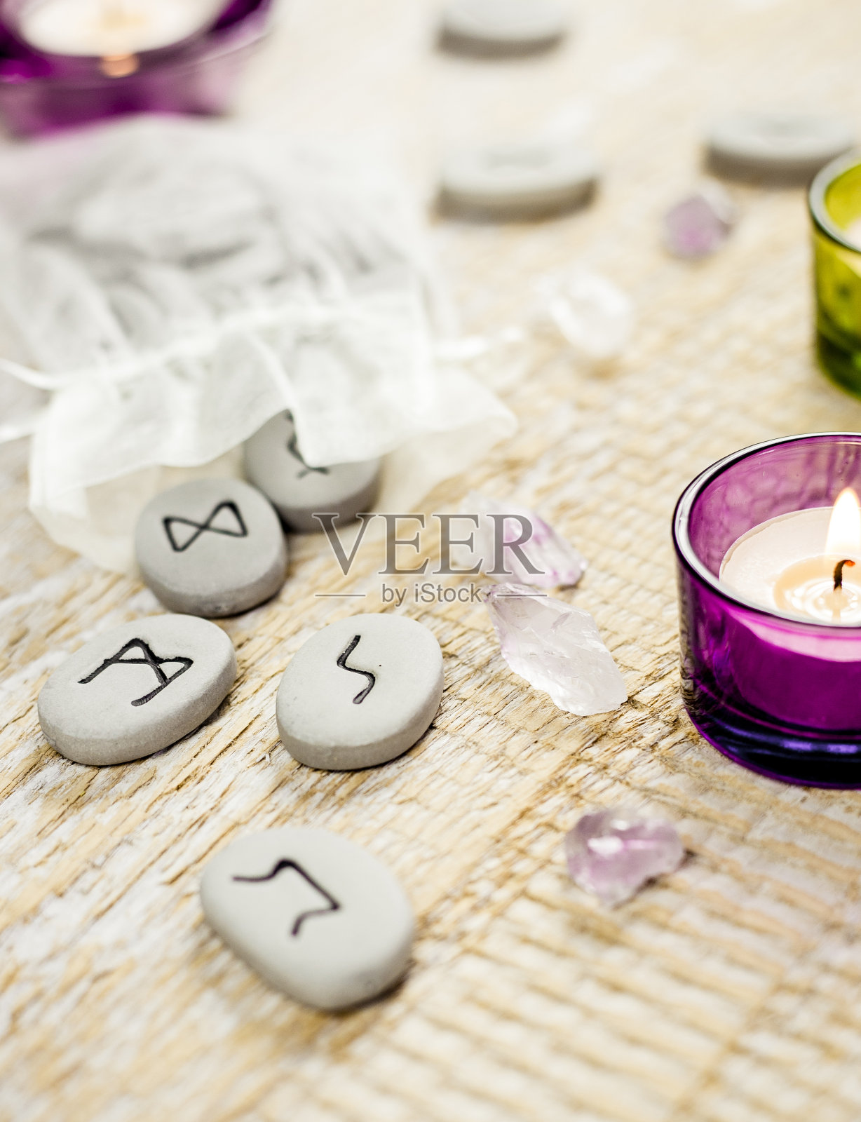木桌上的符文石头。蜡烛在明亮的木制背景上燃烧。照片摄影图片