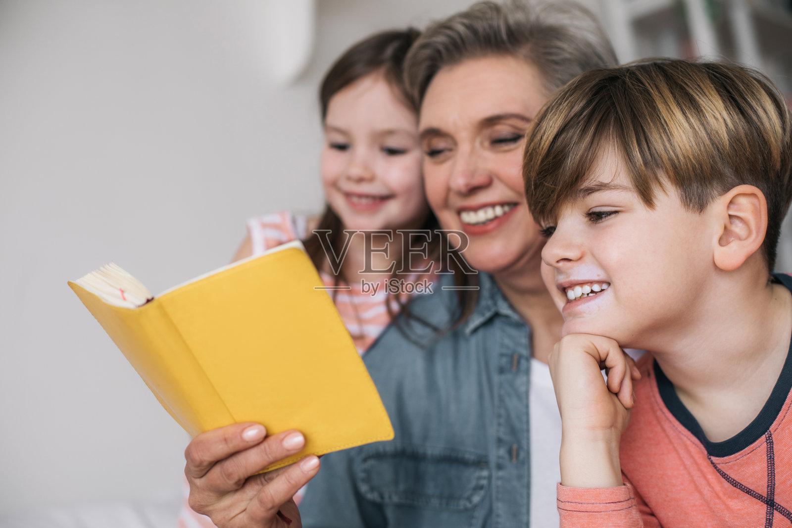 近距离的灰白头发的女人读她的孙子在房子里的书照片摄影图片