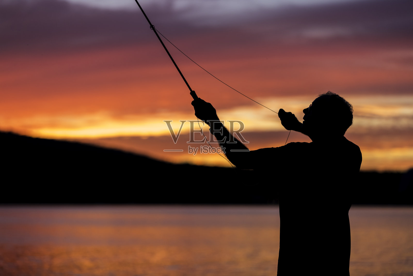 飞钓渔夫在日落湖上的剪影照片摄影图片