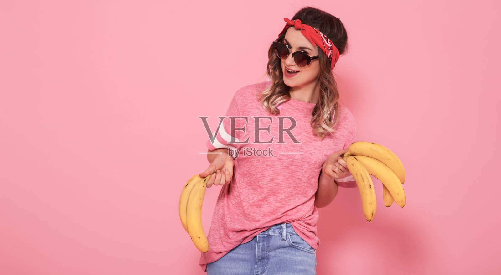 一个女孩的肖像和香蕉孤立在粉红色的背景照片摄影图片