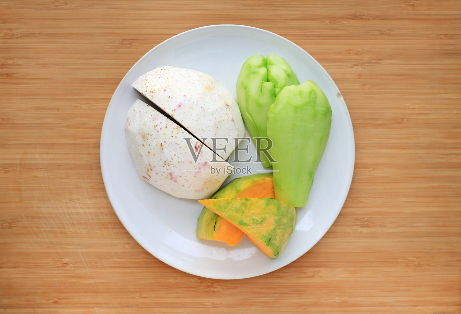 切成薄片的芋头，茶花菜和日本南瓜在塑料托盘上木板背景。照片摄影图片