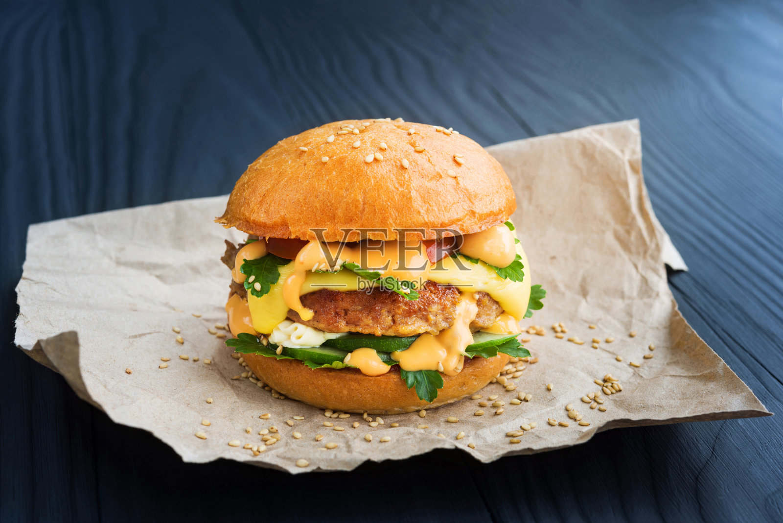 美味的自制汉堡配上西红柿，黄瓜，欧芹，酱汁和奶酪，在一个木制的深色背景。照片摄影图片