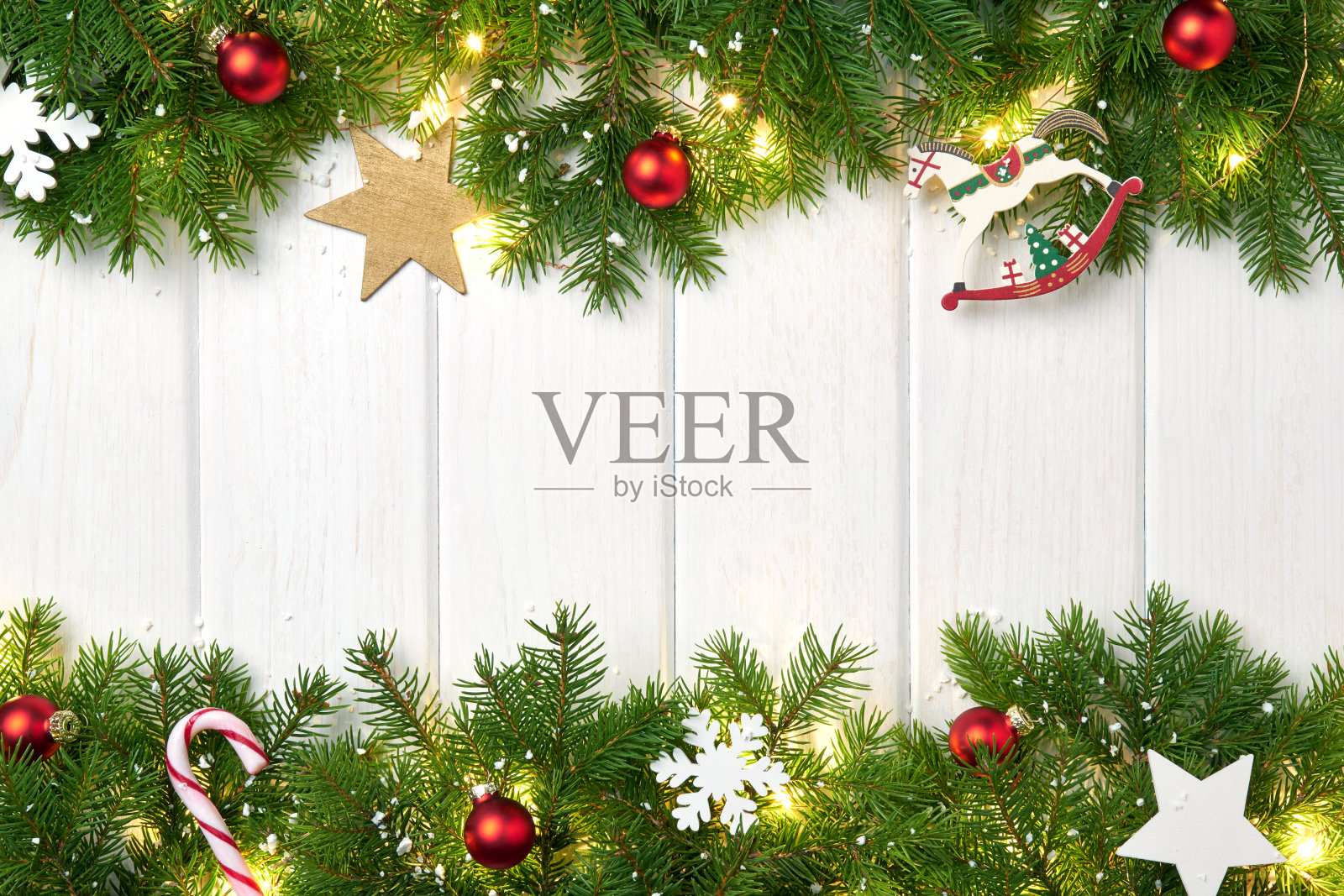 圣诞相框贺卡。在白色的背景上刷一根圣诞树的树枝，上面有红色的球和闪亮的星星、小时、雪花、糖果和圣诞彩灯的花环照片摄影图片