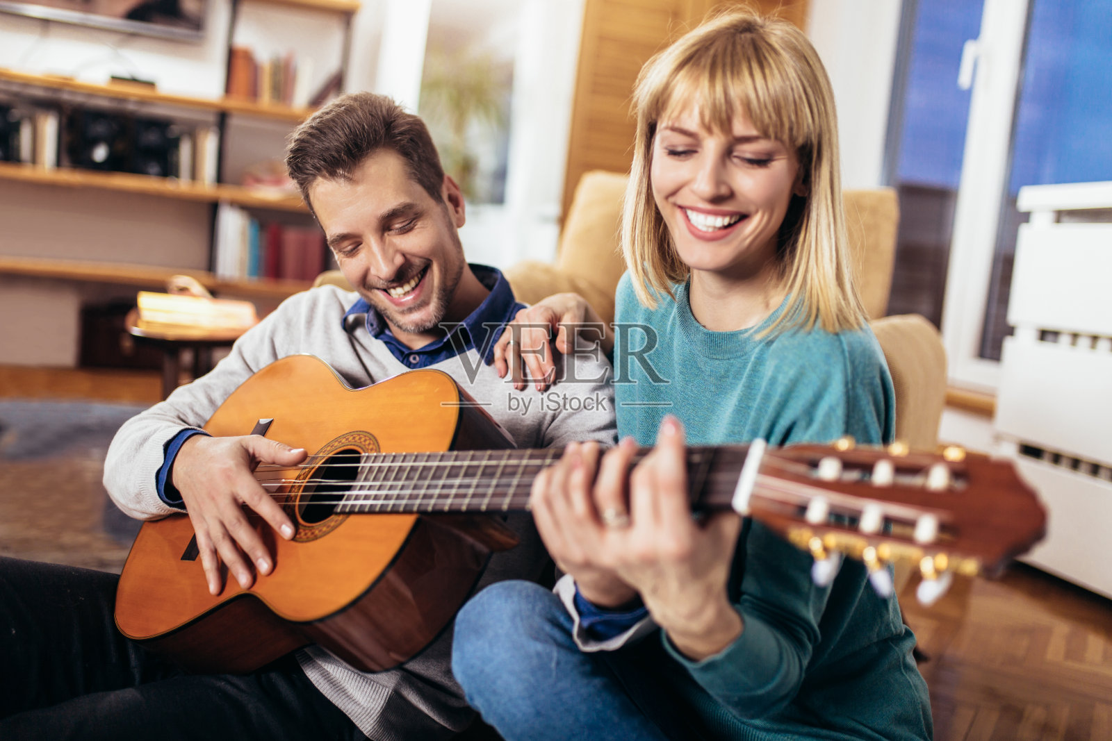 浪漫的情侣在家里玩得很开心，男人在弹吉他照片摄影图片