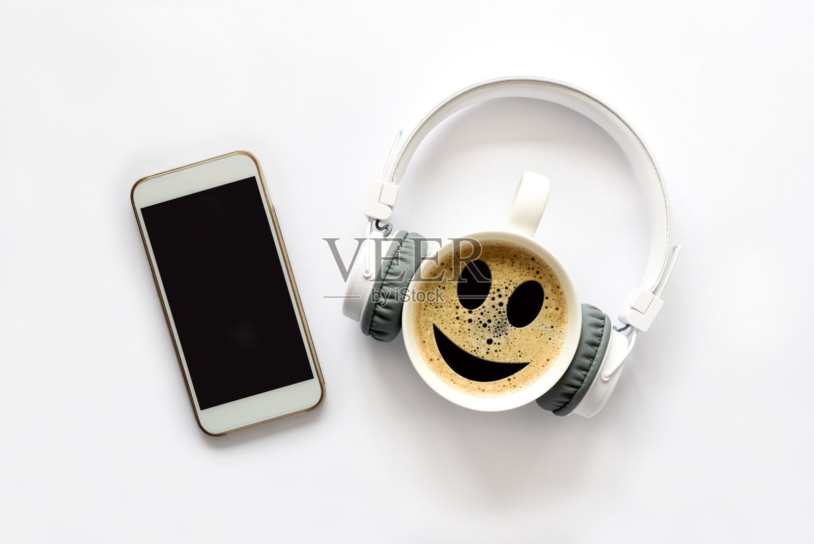 白色智能手机与空白模拟屏幕，耳机，一杯咖啡与笑容在白色背景。前视图。本空间照片摄影图片