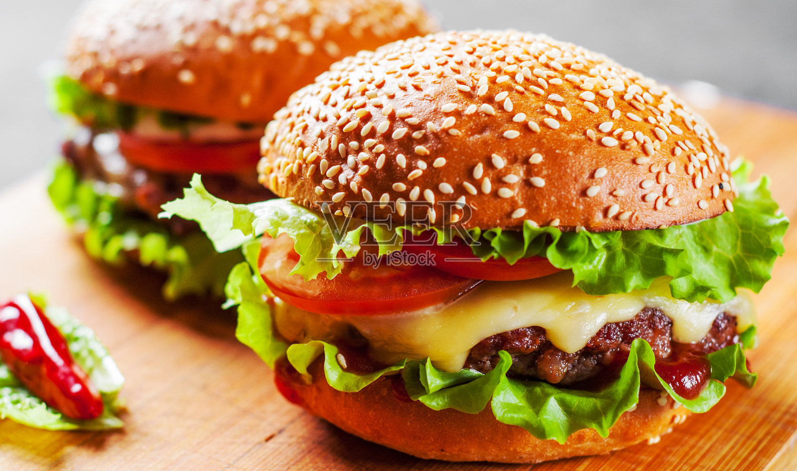 两个汉堡，肉，奶酪和蔬菜放在木板上照片摄影图片