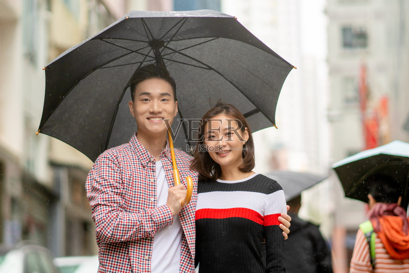 这是一对年轻夫妇在雨中浪漫散步的照片照片摄影图片