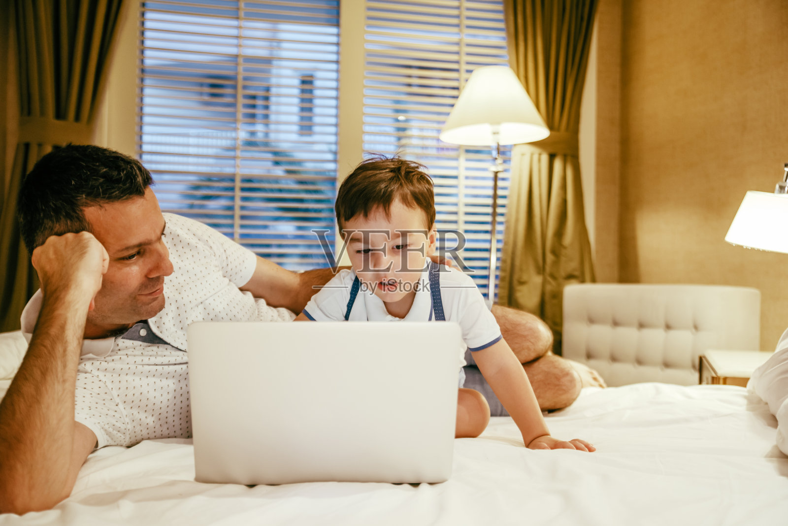 父亲和儿子在床上玩笔记本电脑照片摄影图片