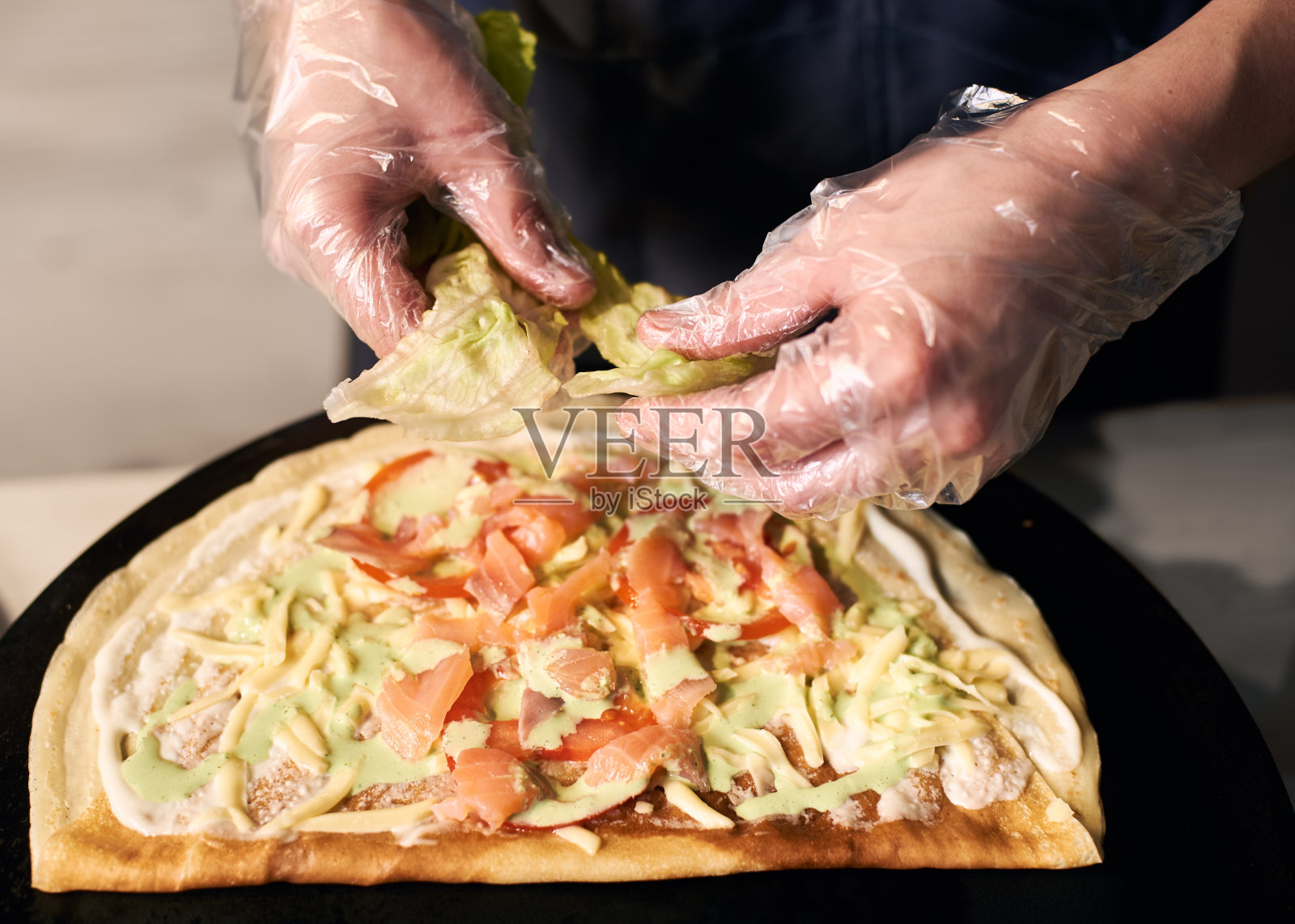 厨师裁切的双手将生菜撕成圆形。披萨烹饪用的切碎的配料。关闭视图照片摄影图片