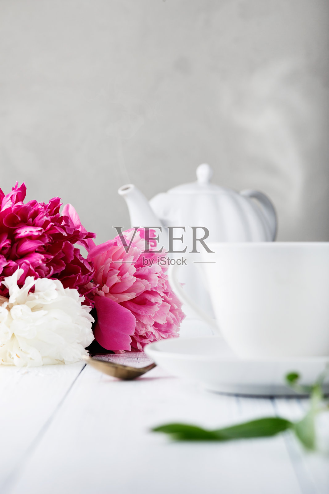 古老的木桌上放着美丽的鲜花、牡丹和白色的陶瓷茶杯，上面放着早餐用的茶照片摄影图片